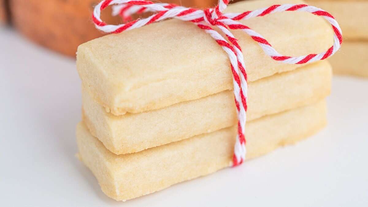 Three rectangular shortbread cookies stacked and tied with a red and white string, featuring pantry staples for easy cookie recipes, placed on a white surface.