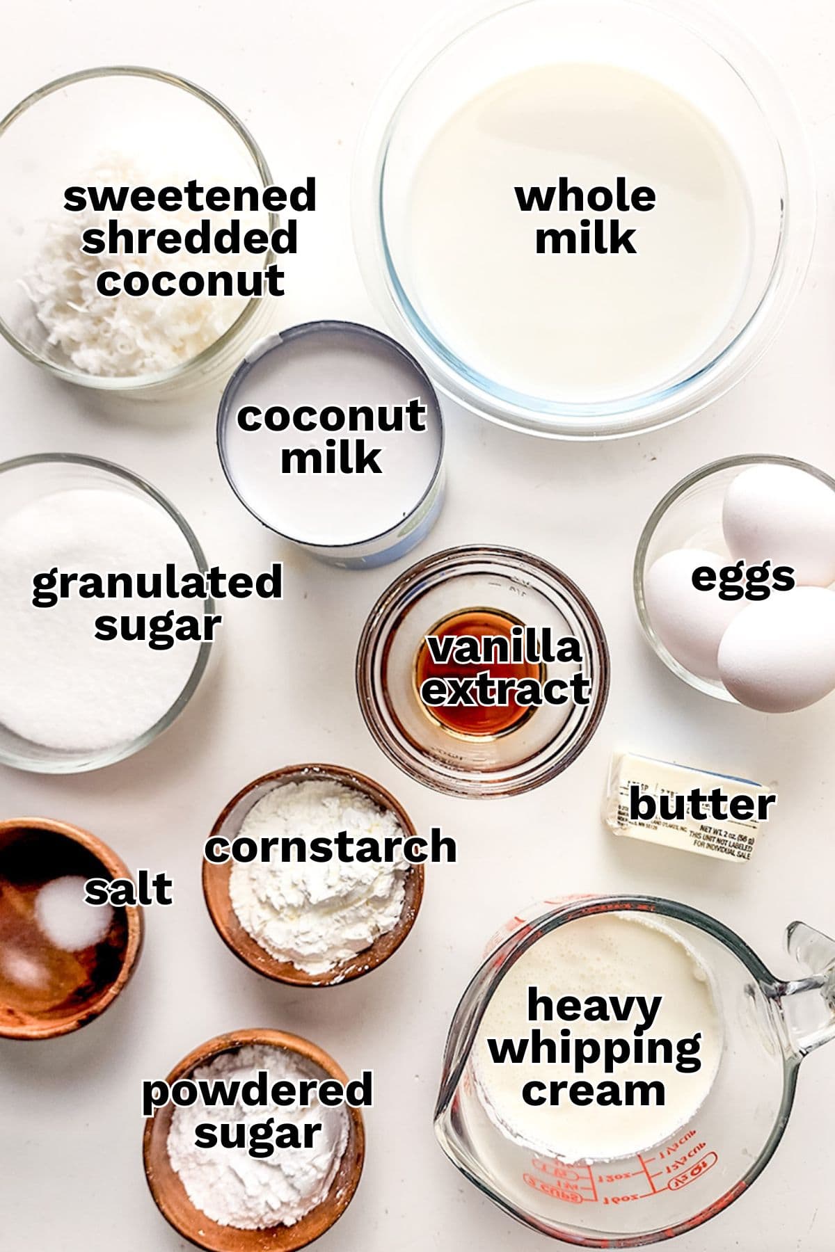 Various baking ingredients in bowls and measuring cups, including whole milk, eggs, butter, granulated sugar, coconut milk, heavy whipping cream, shredded coconut&mdash;everything you need to create a delicious Coconut Cream Pie.