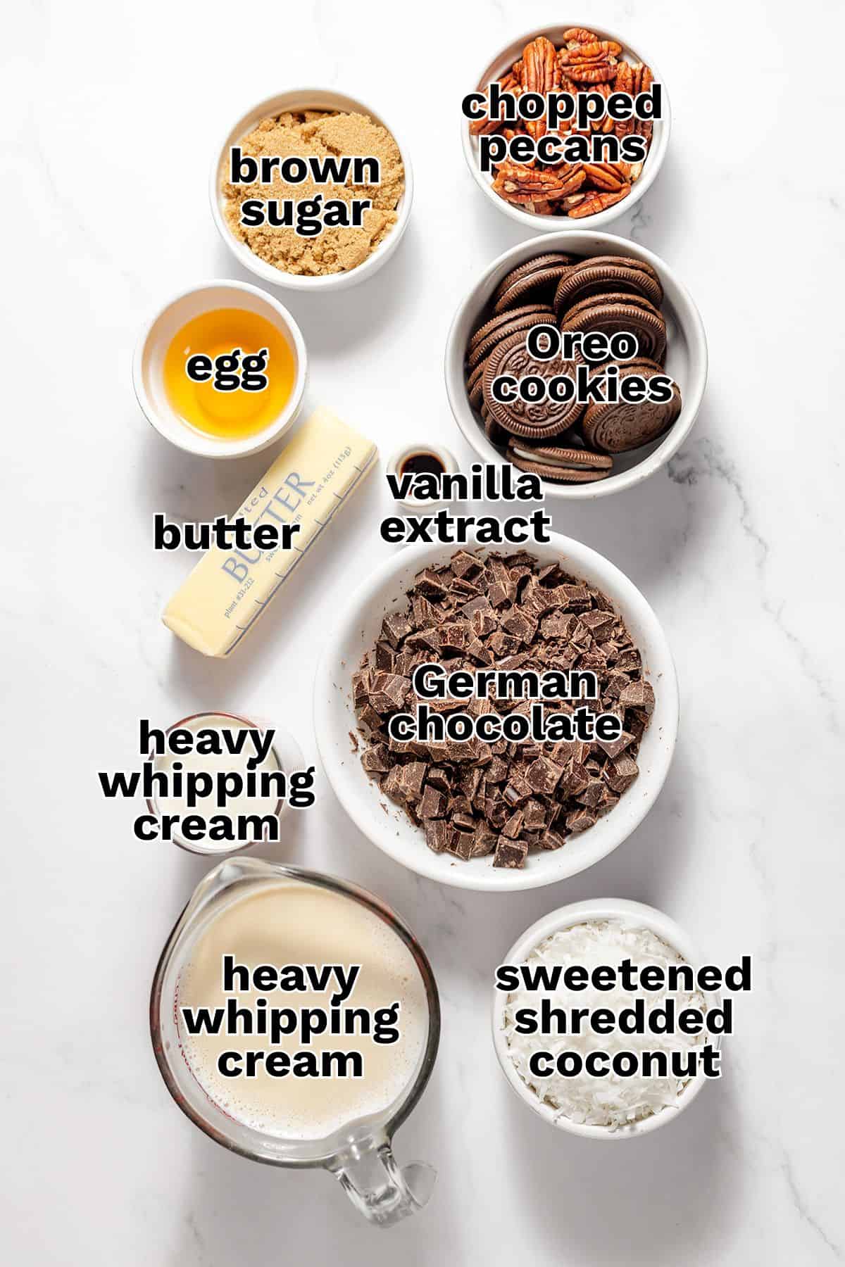 Various baking ingredients labeled: brown sugar, chopped pecans, Oreo cookies, egg, butter, vanilla extract, German chocolate, heavy whipping cream, and sweetened shredded coconut&mdash;perfect for making a classic German Chocolate Pie.