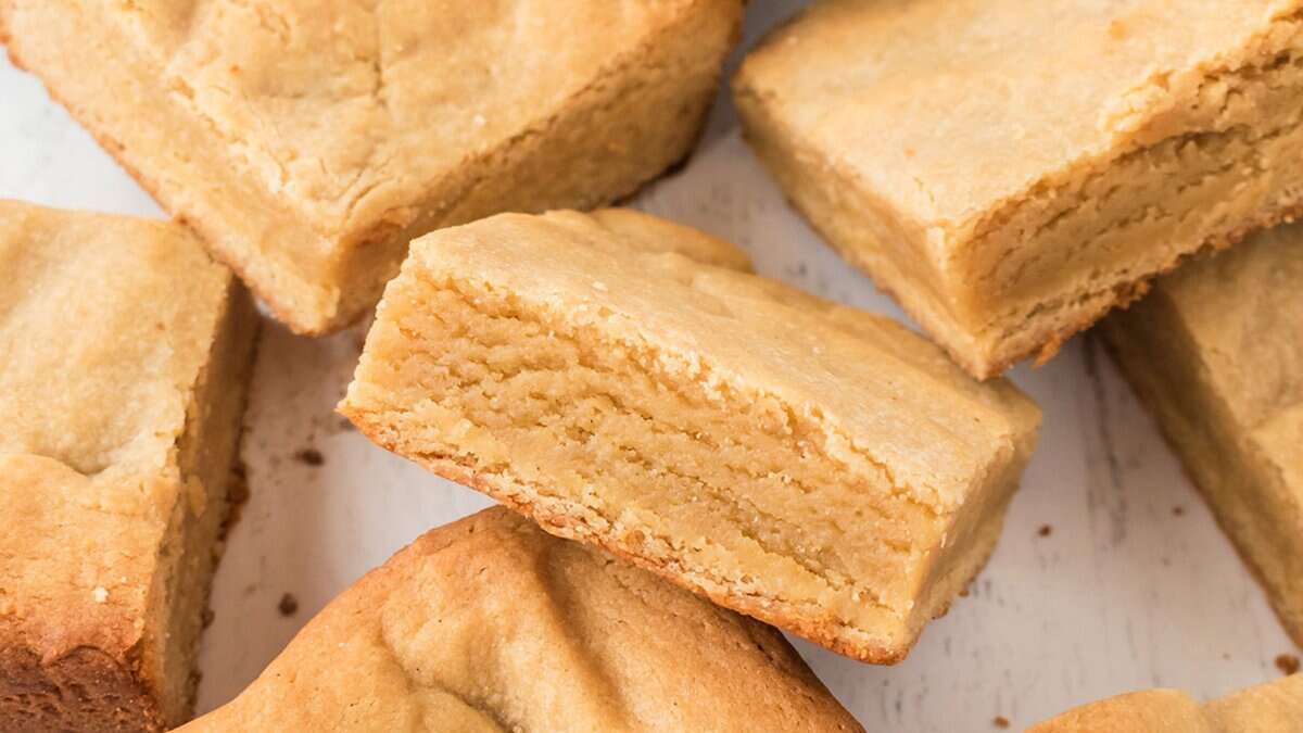 Several pieces of golden brown shortbread are arranged on a white surface, showing their thick, crumbly texture and slightly crisp edges—perfect mini desserts for spring parties or as delightful party desserts.