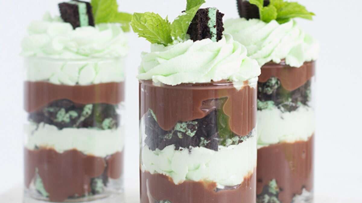 Three clear glasses filled with layers of mint whipped cream, chocolate pudding, and crushed chocolate cookies, topped with whipped cream, a cookie piece, and a mint leaf&mdash;an irresistible choice for easy no bake desserts.