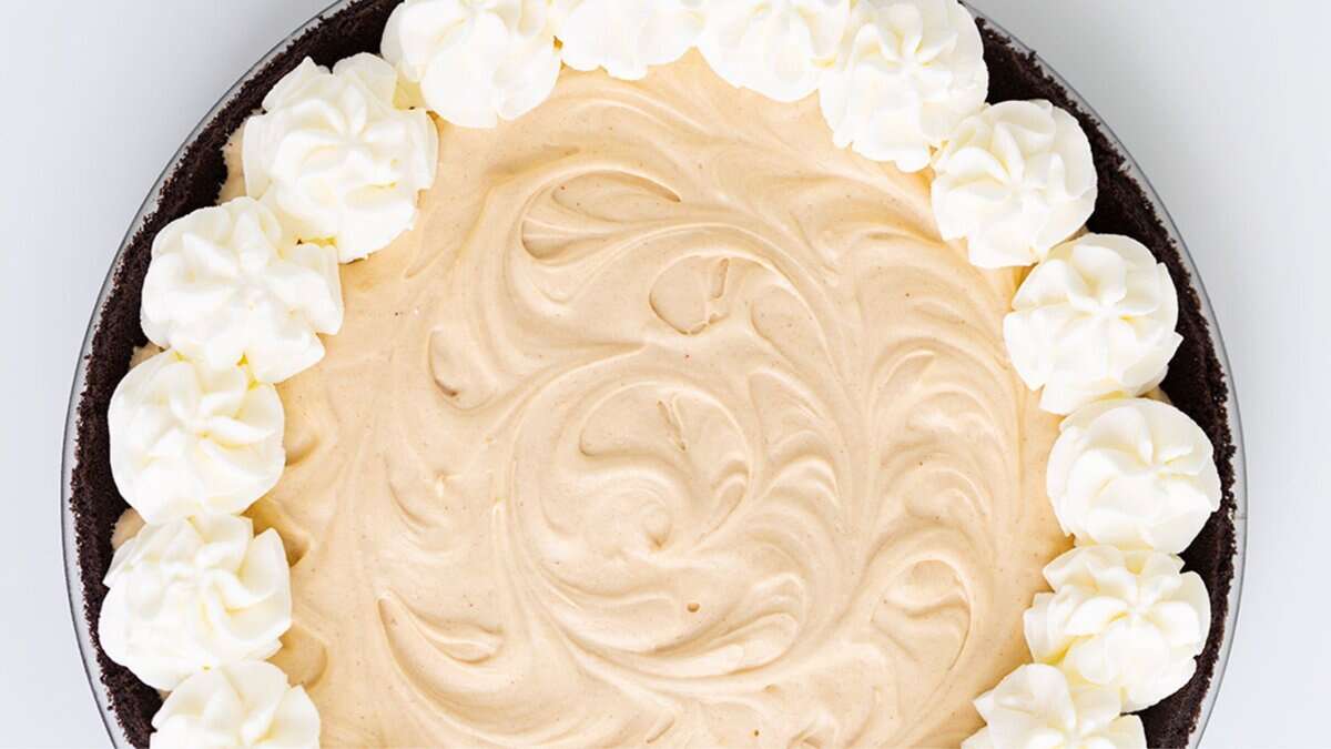 A peanut butter pie with a swirled creamy filling, topped with dollops of whipped cream around the edge, in a chocolate cookie crust&mdash;one of the best no bake desserts for winter.