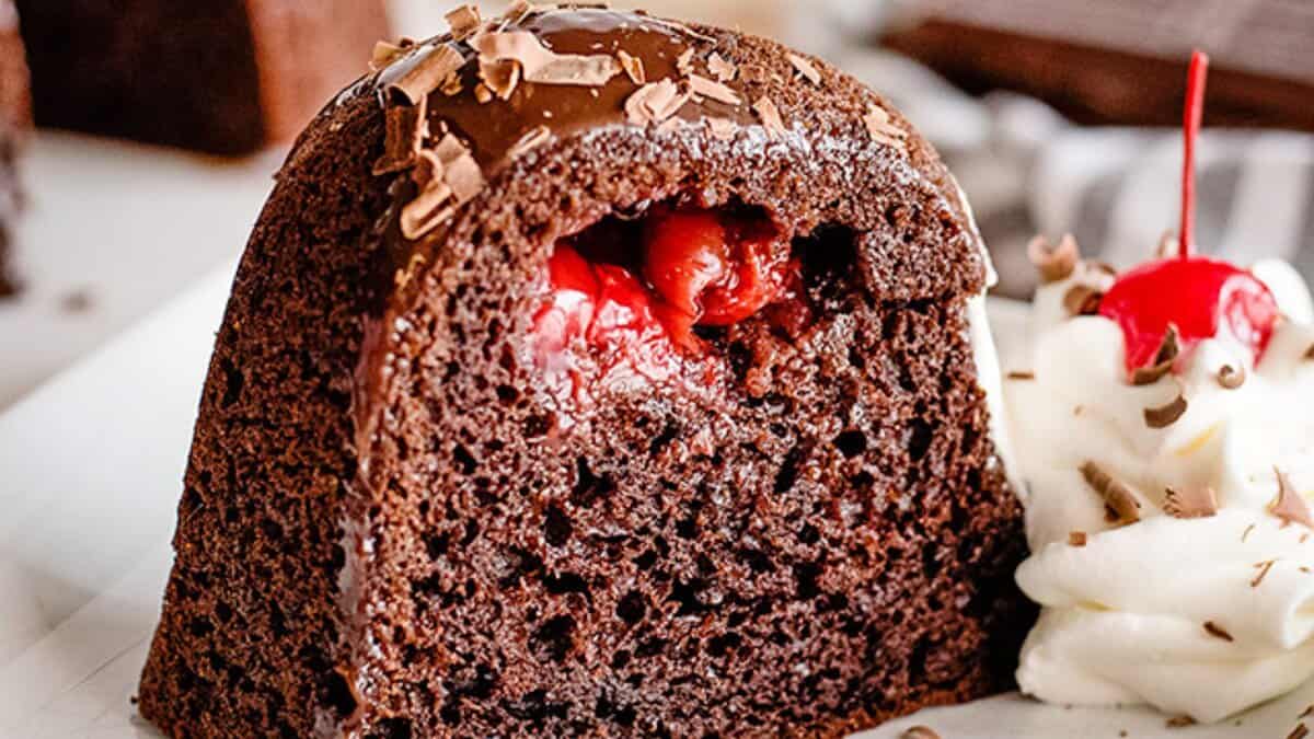 A slice of chocolate cake filled with cherries, topped with chocolate shavings, served with whipped cream and a cherry on the side&mdash;perfect for fans of easy desserts seeking stress-free desserts to enjoy anytime.