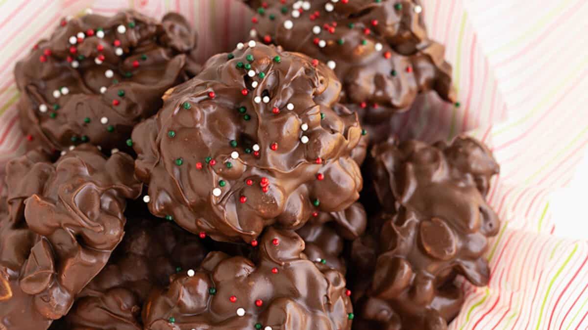 A pile of chocolate clusters with red, white, and green sprinkles on top, placed in a bowl lined with striped paper&mdash;perfect for those seeking stress-free desserts during the holidays.