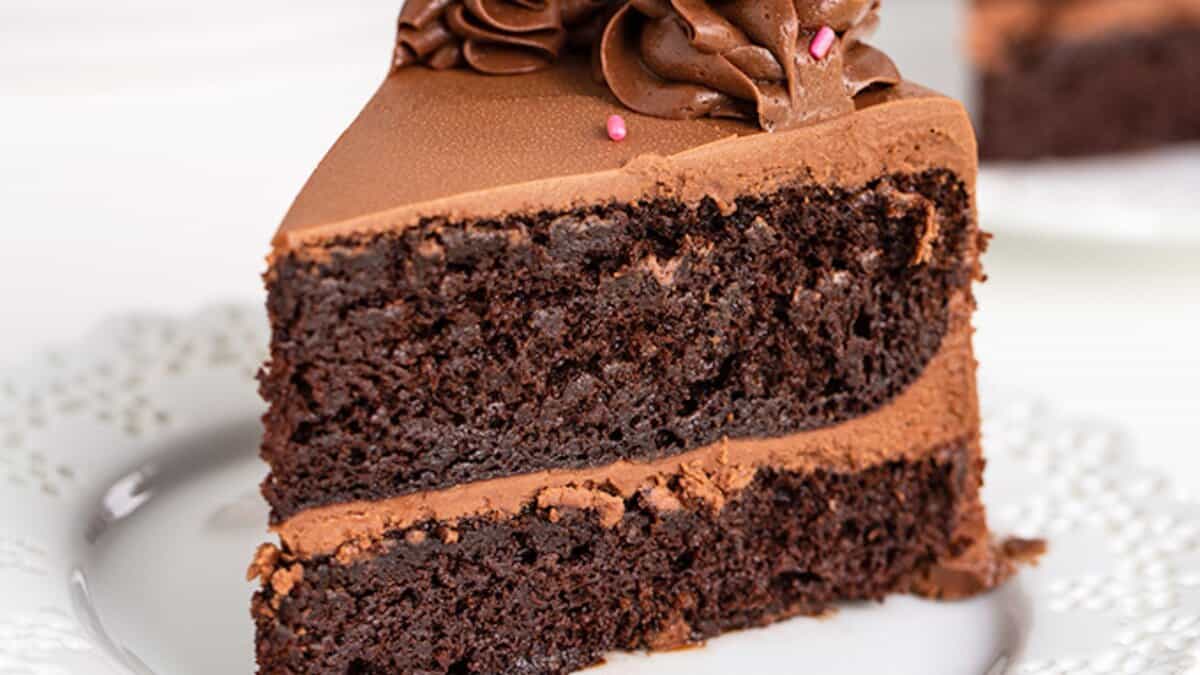 A slice of double-layered chocolate cake with chocolate frosting on a white plate&mdash;perfect for those seeking stress-free desserts.