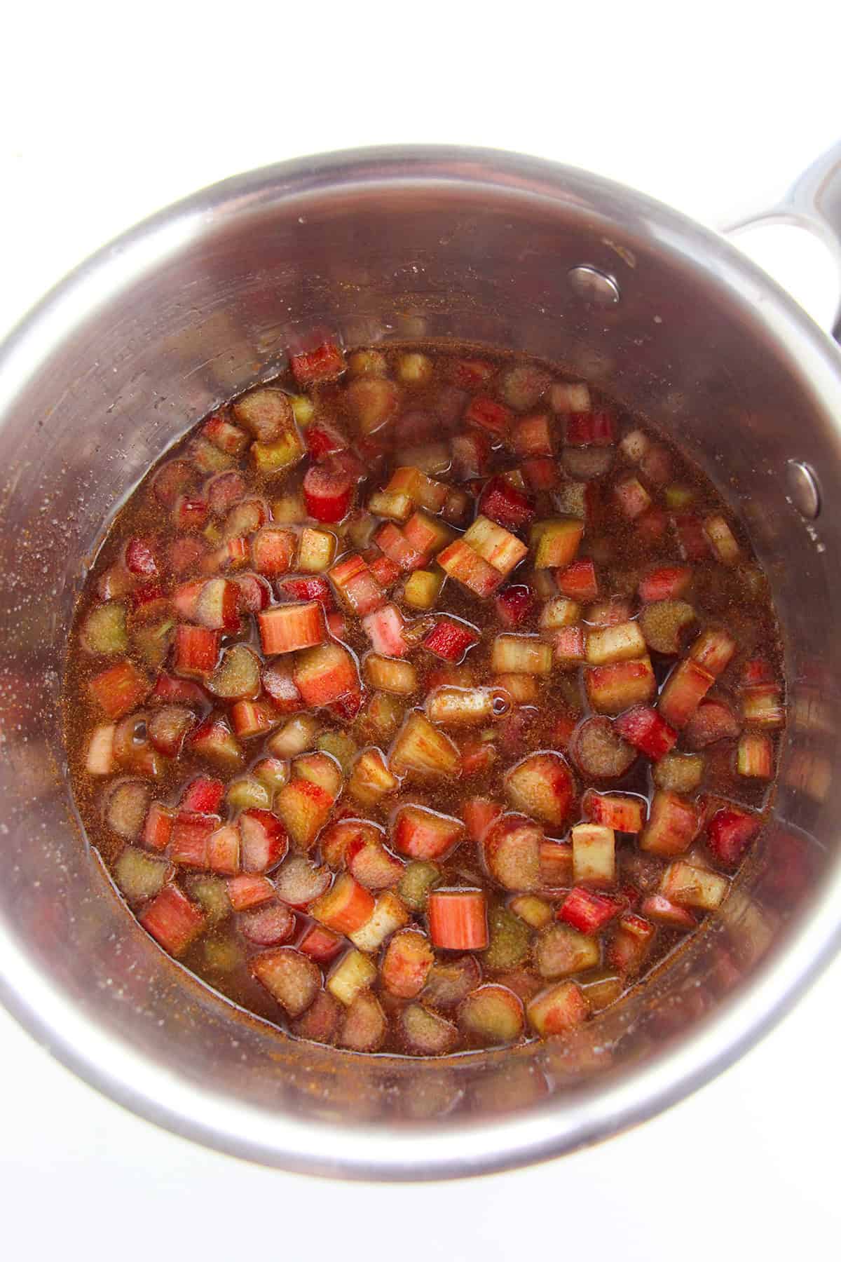 A stainless steel pot filled with chopped rhubarb simmering in a liquid mixture, perfect for making classic Stewed Rhubarb.