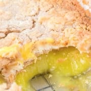 A close-up of a lemon dump cake in a glass dish, featuring a crumbly topping and gooey yellow filling, partially scooped out to reveal its luscious layers.