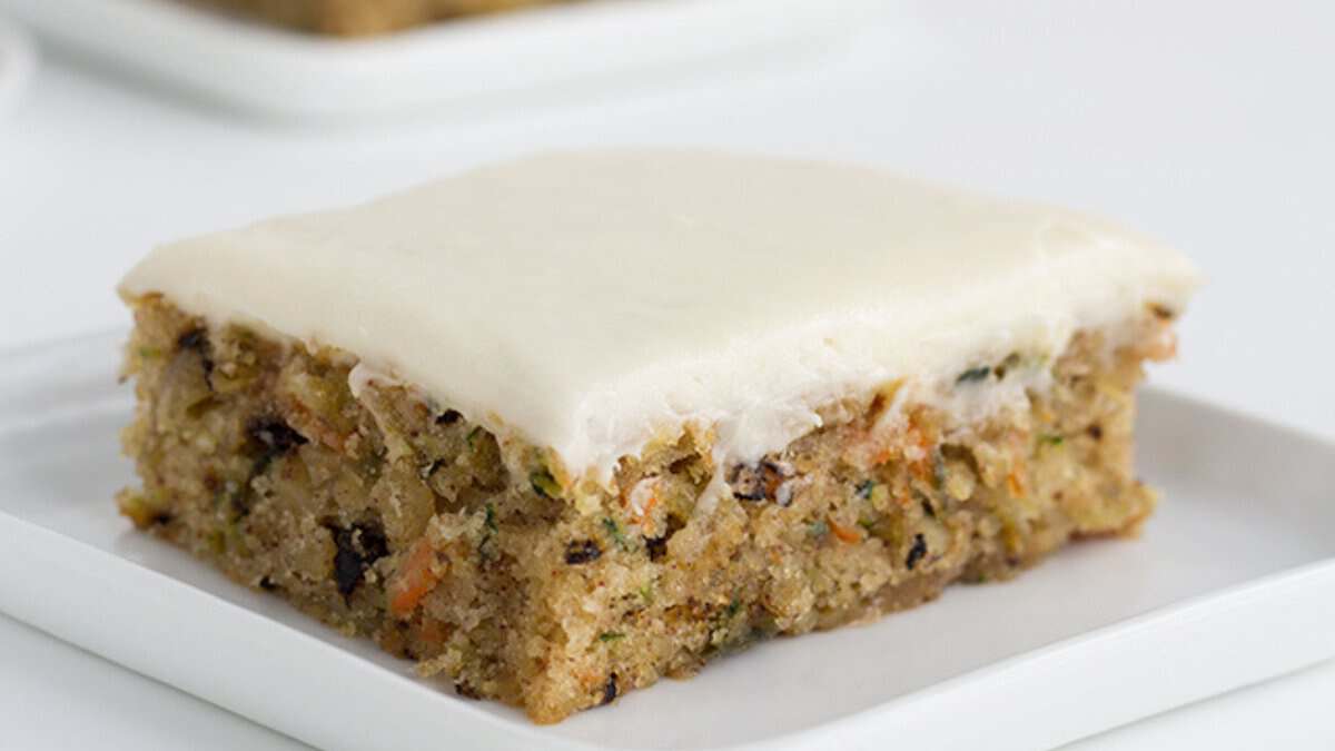 A square slice of frosted carrot cake with visible pieces of carrot and nuts, served on a white plate&mdash;one of those easy desserts anyone can make for a stress-free treat.