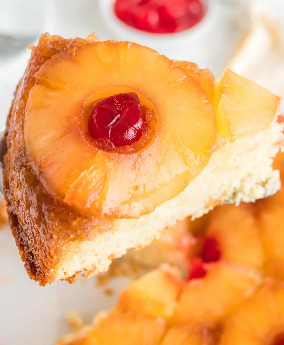 A close-up of a pineapple upside down cake slice, topped with a caramelized pineapple ring and maraschino cherry, made easy with cake mix.
