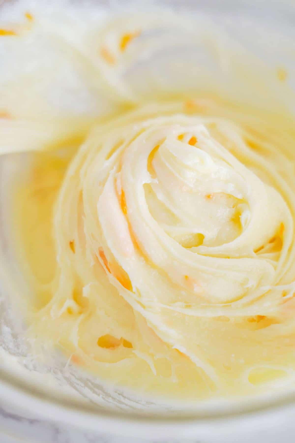Close-up of creamy, swirled butter and sugar mixture in a mixing bowl, ready to be transformed into delicious orange creamsicle cookies.