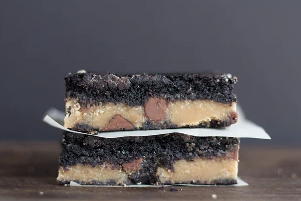 Two stacked chocolate peanut butter brownies with a layer of peanut butter and chocolate chips.