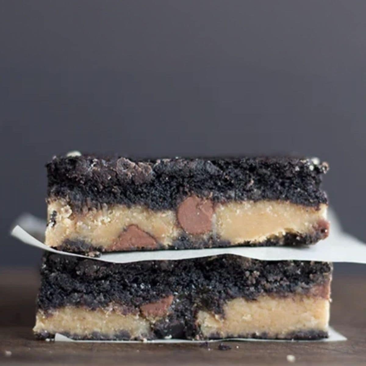 Two stacked fudge brownie bars layered with cookie dough and chocolate chips.